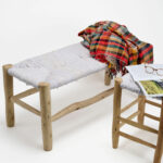Banc marocain traditionnel en bois d’eucalyptus. Son assise est tissée en laine blanche
