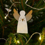 Petit ange gardien en porcelaine blanche, motif coeur et ailes en papier.Il est fixé à un cordon en métal doré.Objet poétique, il saura trouver sa place sur votre sapin de Noël.