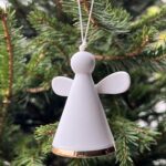 Petit ange gardien en porcelaine blanche,Il est équipé d’une petite clochette pour accompagner l’esprit joyeux des fêtes de fin d’année. Objet poétique, il saura trouver sa place sur votre sapin de Noël.