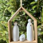 Crèche en bois d’acacia avec les trois figurines de la nativité en porcelaine blanche à suspendre.Style très épuré qui s’intègre parfaitement avec tous types d’intérieurs.