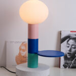 Magnifique lampe ” Agathe” de la marque Ciluzio d’AAMA Design. Elle est composée d’un socle subtilement moucheté et d’un empilement de 3 cylindres (dont un avec un petit plateau), le tout surplombé par un globe opaline translucide qui diffuse une lumière douce et subtile.